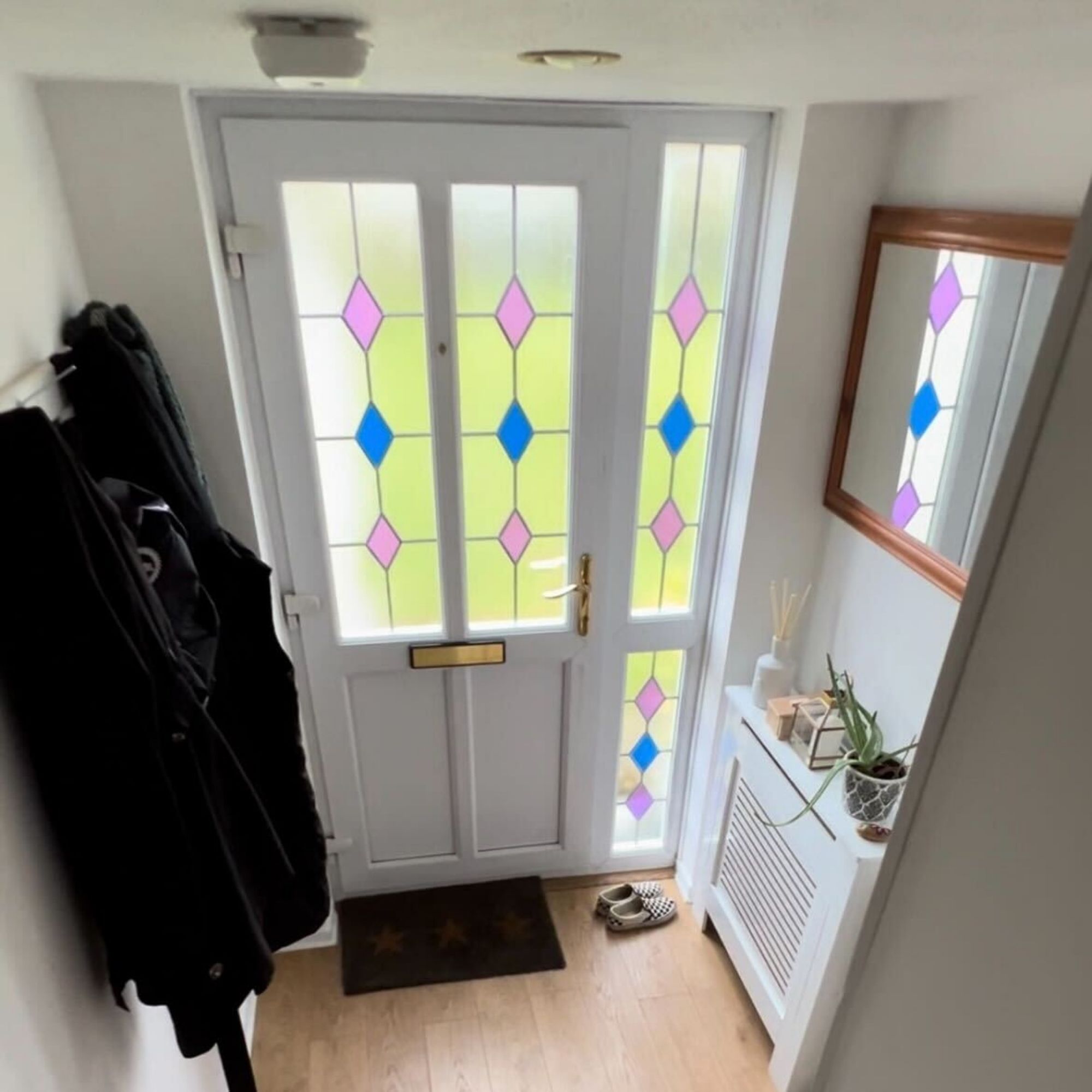 A small, white hallway with light wood, laminate flooring.