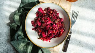 Bowl of beetroot salad with fork sitting on chopping board