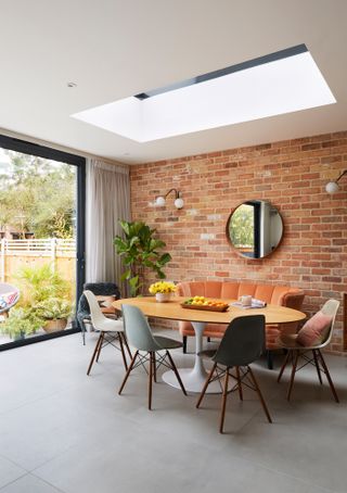 Dani Ellis home: dining area of open plan space with round table against exposed brick style wall