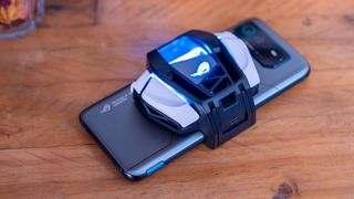 En Asus ROG Phone 6D Ultimate med MediaTek Dimensity ligger på ett bord med en AeroActive Cooler 6 fäst på baksidan.