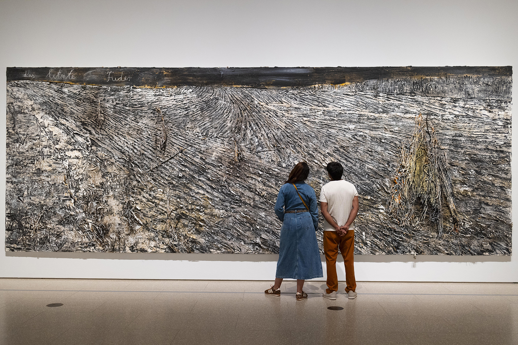 people looking at large textured painting