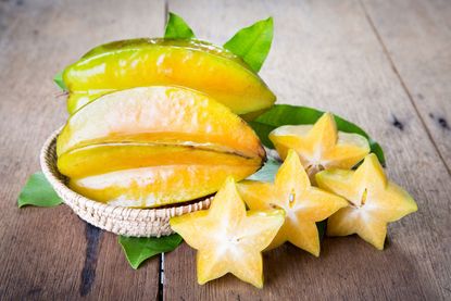Star Shaped Starfruit Pieces Next To Whole Starfruits