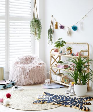 Reading corner with bookshelf, hanging plants, rug and pompoms by Dunelm