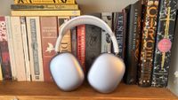 Apple AirPods Max 2 wireless headphones in front of a shelf full of books