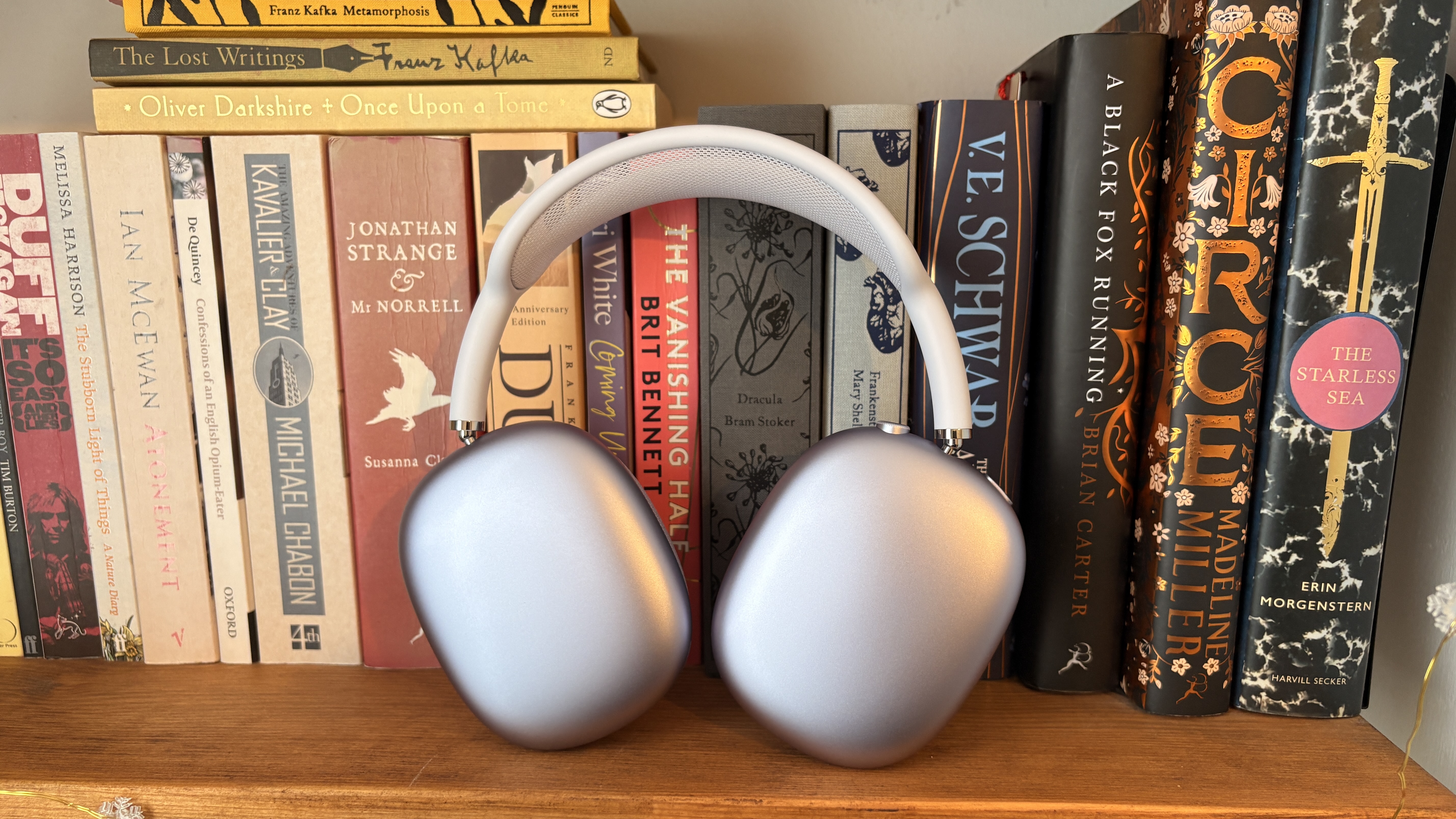 Apple AirPods Max 2 wireless headphones in front of a shelf full of books