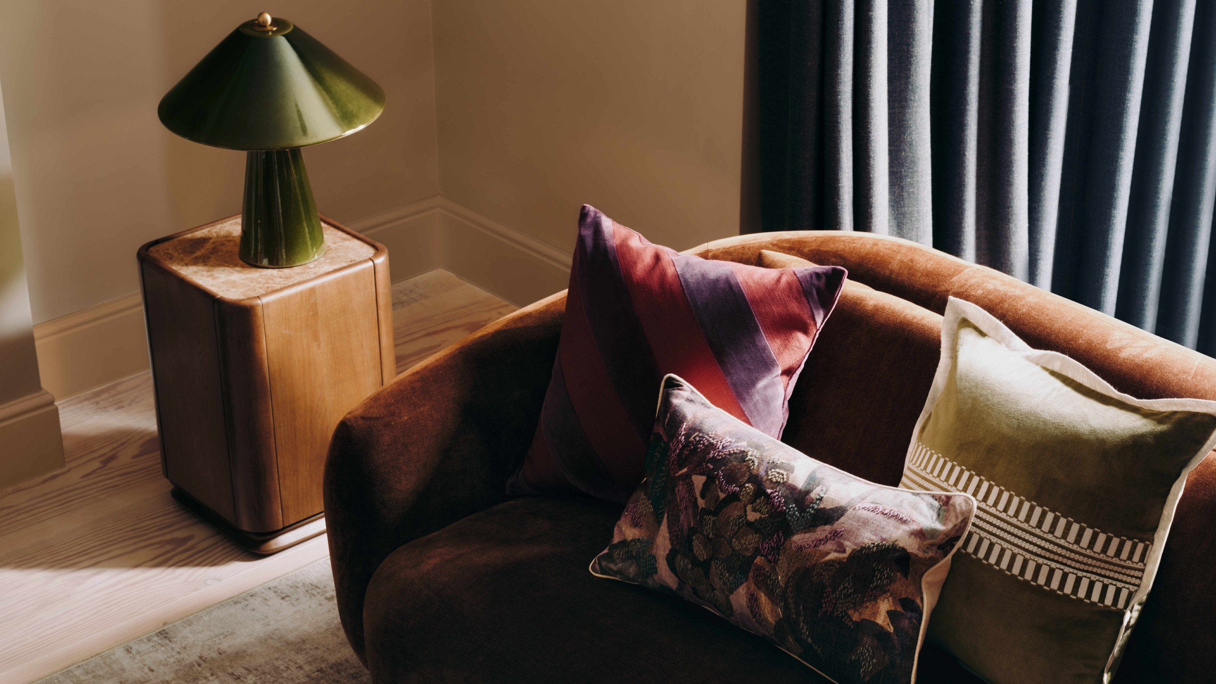 M&amp;S All Over Ceramic Table Lamp in green on a dark wood side table next to a brown velvet sofa with patterned cushions
