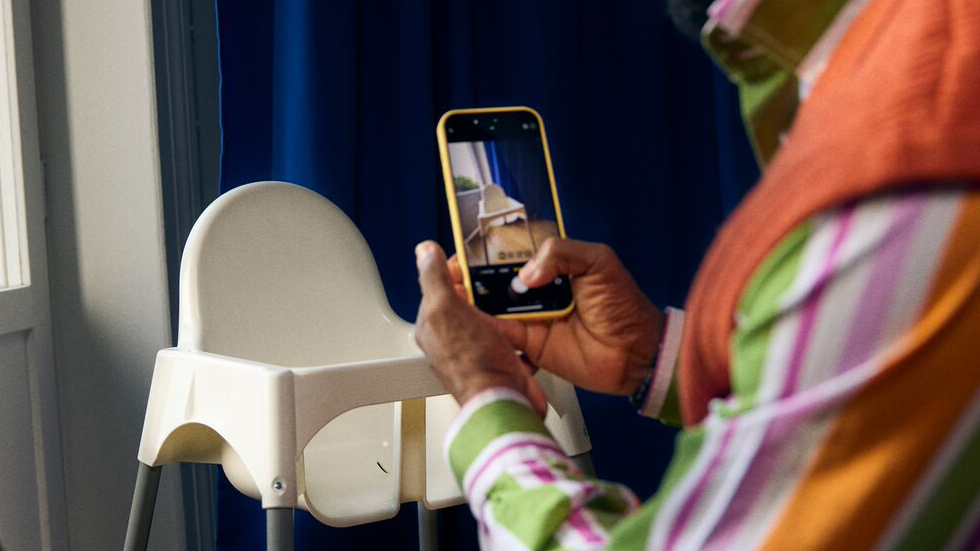 A man holding a phone taking a photo of IKEA furniture