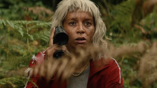 Alfie Williams as Spike, wearing a blonde wig and red tracksuit