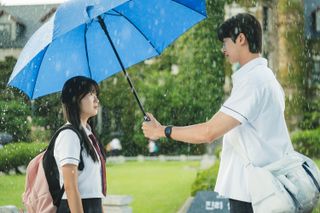 A boy (Byeon Woo-seok as Ryu Sun-jae, right) holds an umbrella over a girl's (Kim Hye-yoon as Im Sol, left) head, in the k-drama 'Lovely Runner'