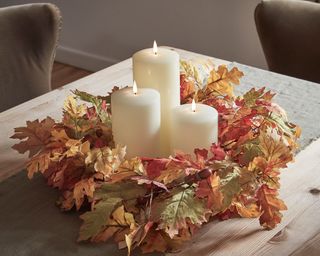 Autumn leaves in a wreath used as a table centrepiece with candles