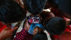 Children watch a video of a traditional Waiapi dance on a smartphone in the Waiapi indigenous reserve in Amapa state, Brazil 