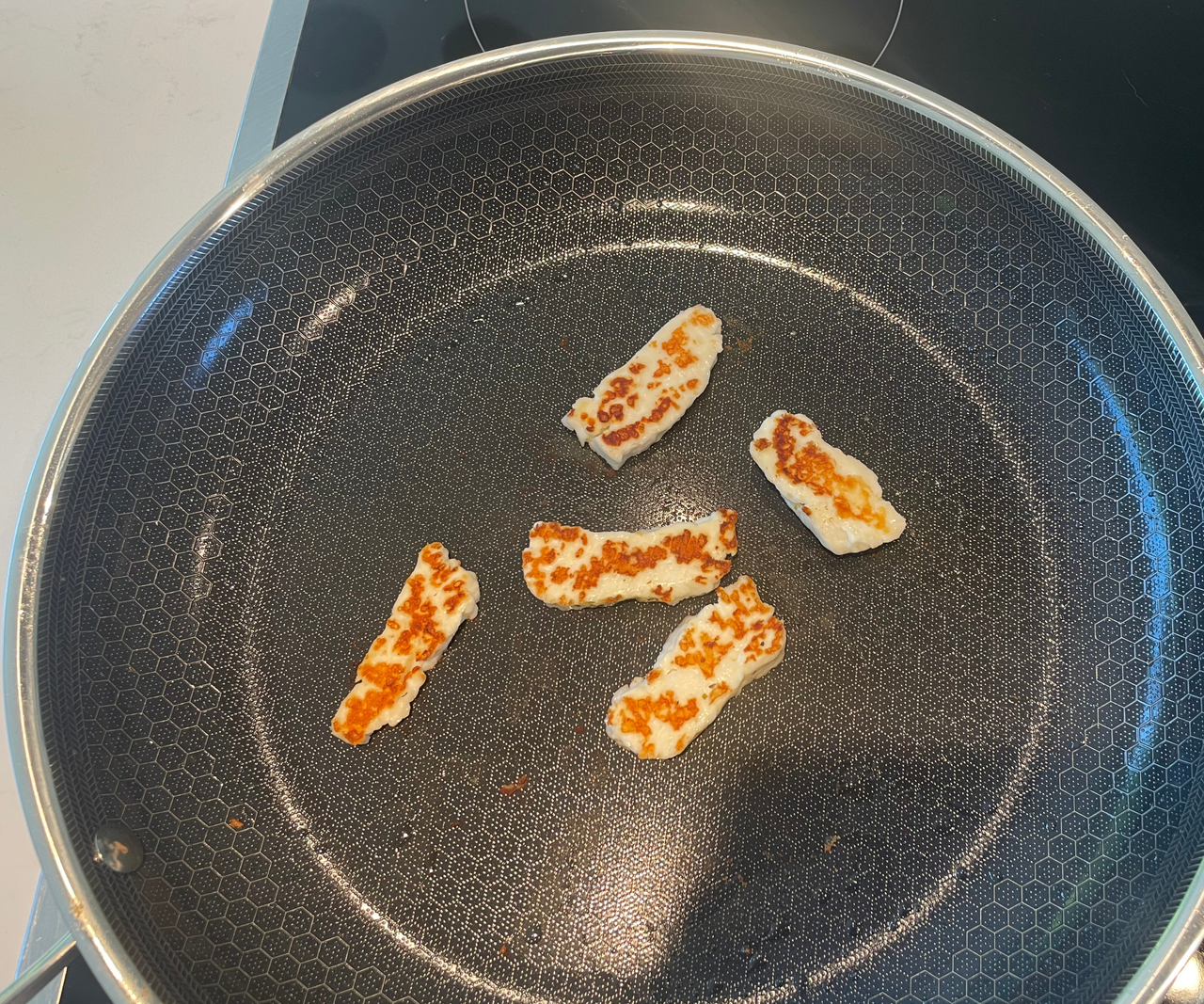 Halloumi frying in a HexClad Hybrid Frying Pan, with a golden sear.