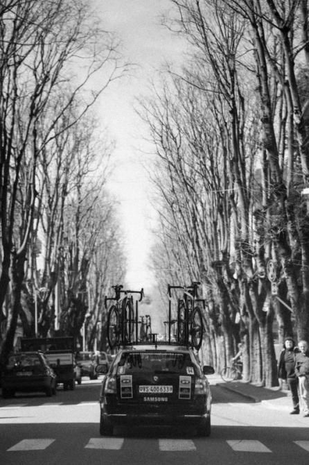 The race heads down a tree-lined street in Italy.