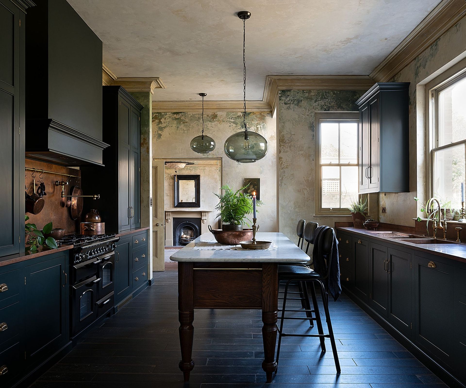 A moody victorian kitchen with dark green cabinets and copper countertops