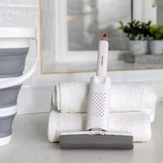 Lakeland mini window mop leaning against white towels and next to a bucket