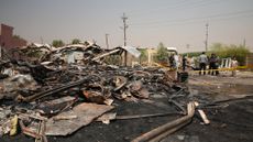 Iraqis inspect damaged structures at the site of an airstrike on a Popular Mobilization Forces base in Mosul, Iraq
