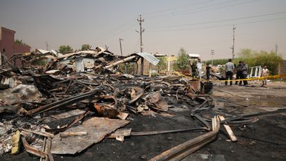 Iraqis inspect damaged structures at the site of an airstrike on a Popular Mobilization Forces base in Mosul, Iraq