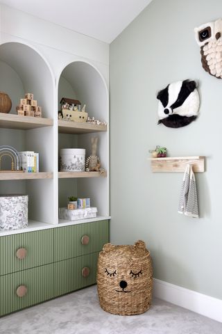 A corner of a kids room where there's built in storage and animal wall decor