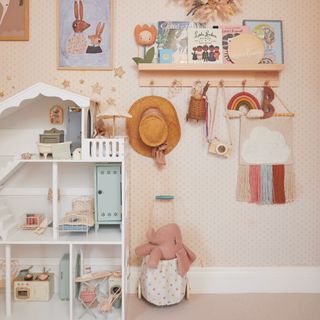 Pink children's room with dolls house and artwork on the walls