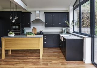 An example of kitchen styles showing a kitchen with a wooden island, wooden flooring and black cabinets