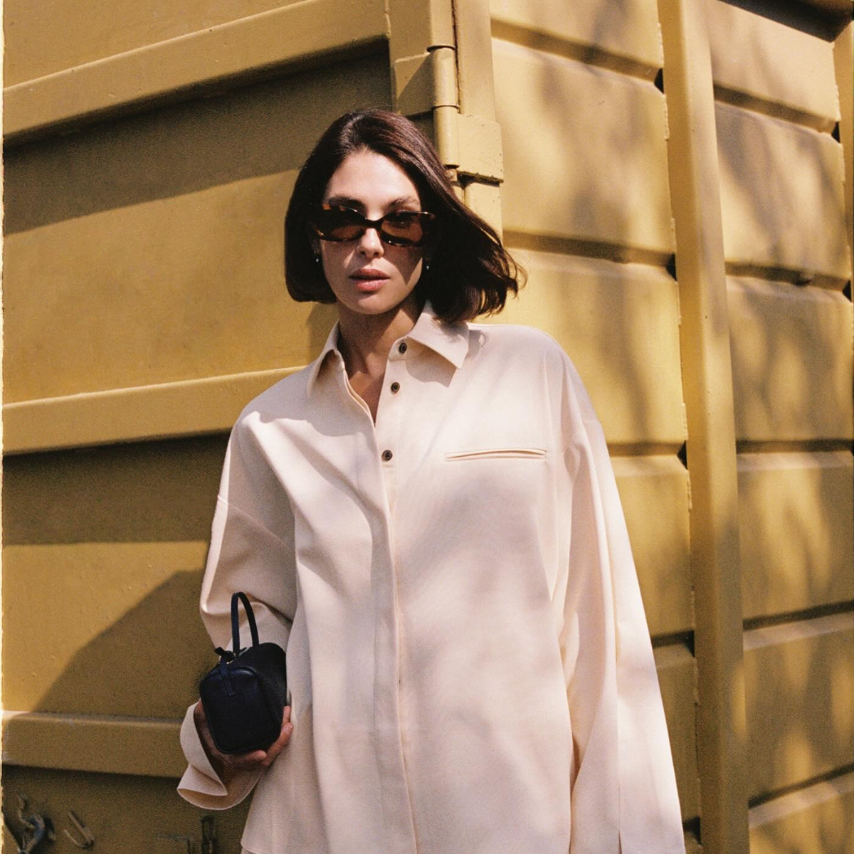 A woman stands outside in sunglasses