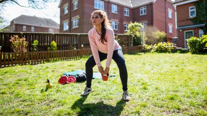 A woman completing a kettlebell workout outside 