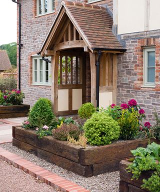 A front garden with two rustic looking raised beds made of untreated railway sleepers