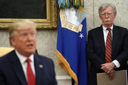 White House National Security Advisor John Bolton (R) listens to U.S. President Donald Trump as he and Dutch Prime Minister Mark Rutte talk to reporters in the Oval Office at the White House 
