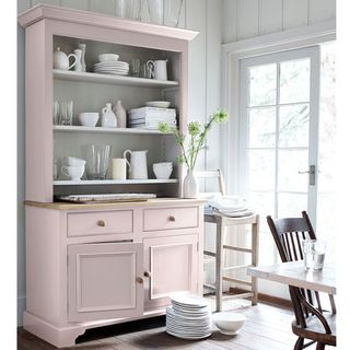 room with pink wooden shelf with white dishes and wooden flooring