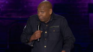 Dave Chappelle shrugs during his set in Dave Chappelle: The Dreamer.