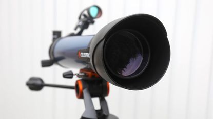 a telescope in front of a white fence