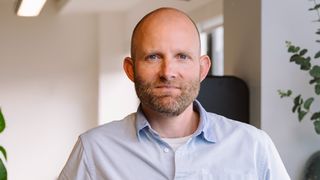 A head and shoulders photo of Qodea&#039;s CEO, Tom Ray. He is facing directly towards the camera wearing a light blue shirt.