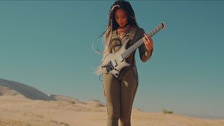 Chena plays a headless guitar in the desert