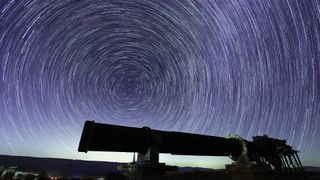 View of star trails and Perseid meteors, over an old quarry oven, in Makhtesh (crater) Ramon, the Negev Desert, Southern Israel.