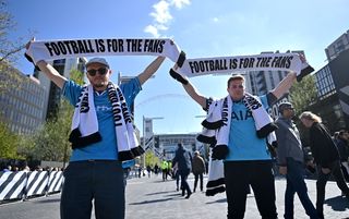 A Manchester City supporter and a Tottenham supporter holding aloft scarves that say 'Football is for the fans'