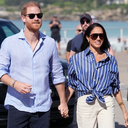 Prince Harry and Meghan Markle wearing sunglasses walking outside