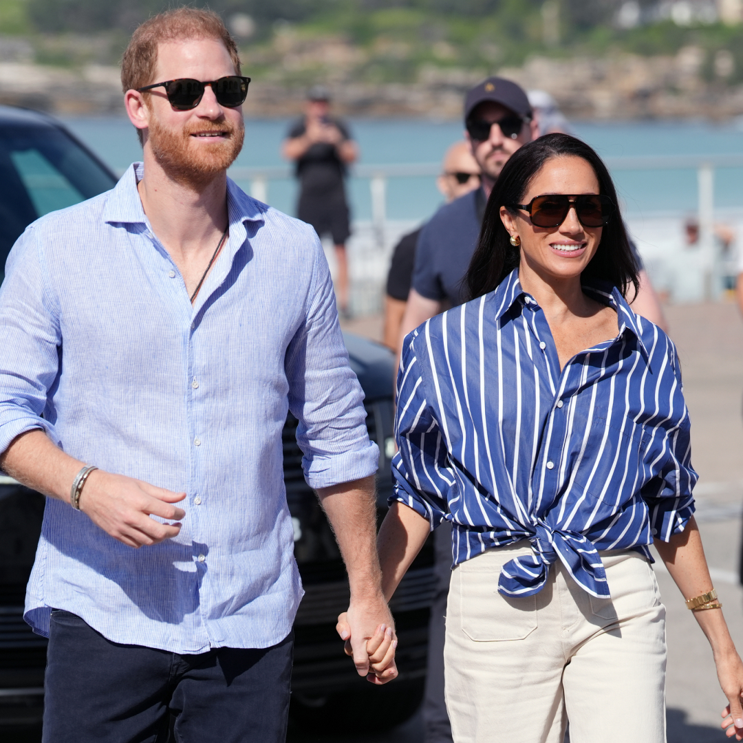 Prince Harry and Meghan Markle wearing sunglasses walking outside