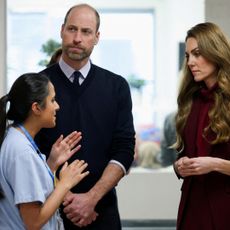 Prince William and Princess Kate speak with a nurse in a blue uniform.