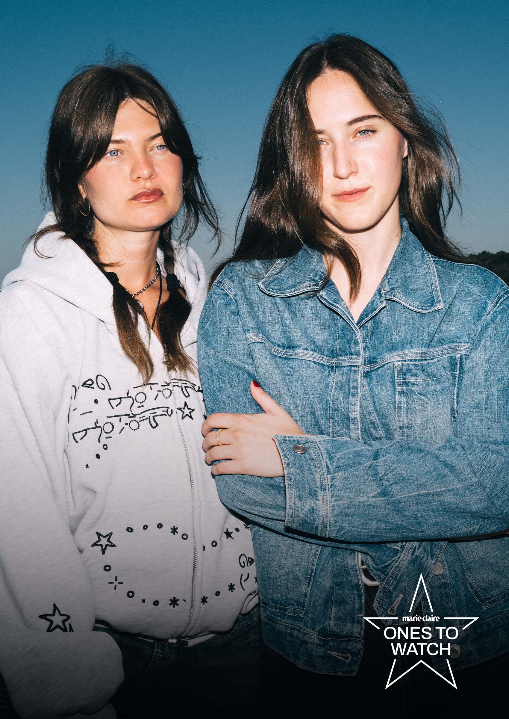 songwriters elvira and luka kloser pose together against a setting blue sky