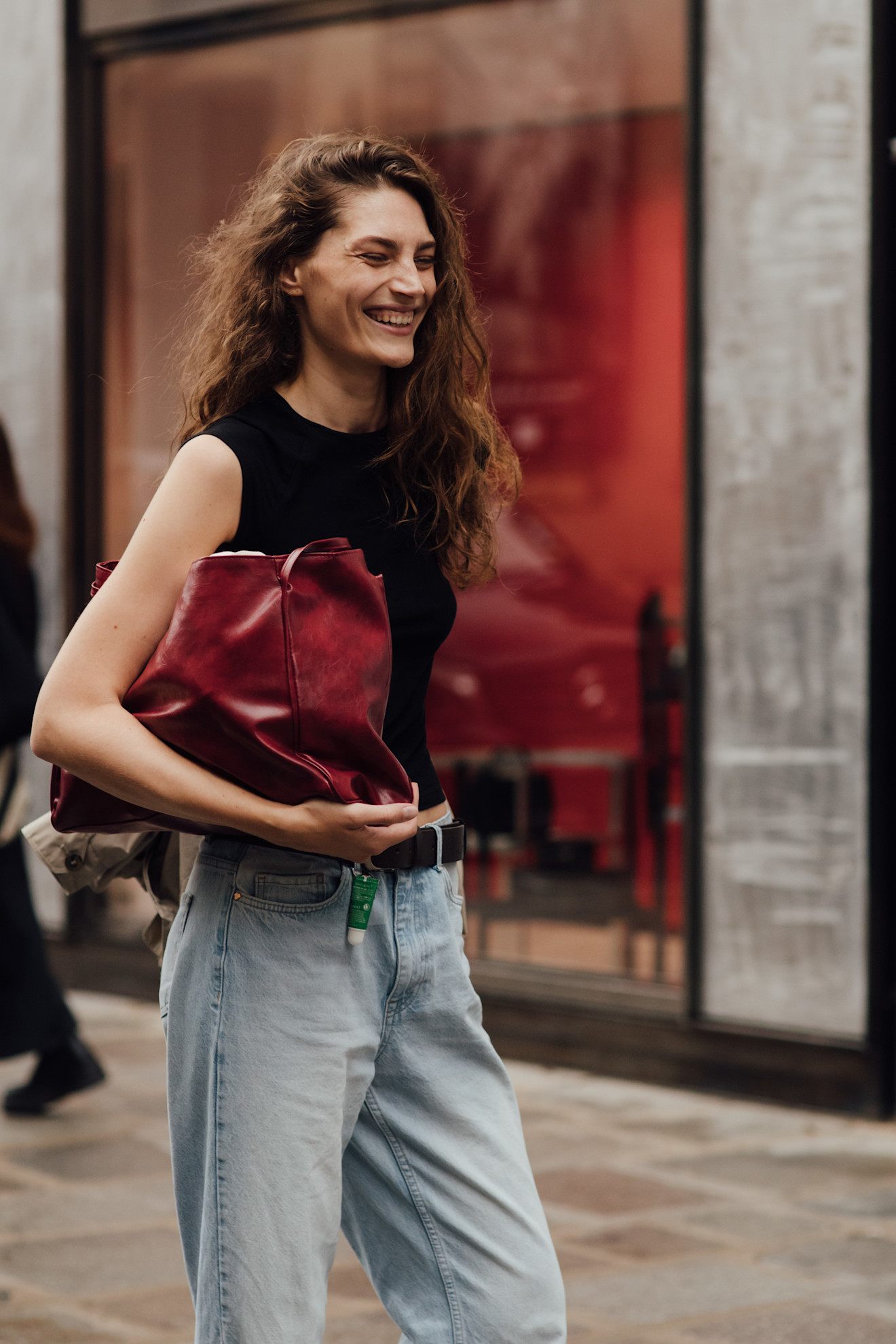 Paris Fashion Week attendee wears blue jeans with a red clutch bag.