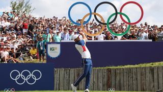 Scottie Scheffler tees off in front of a huge crowd and the Olympic rings at Le Golf National