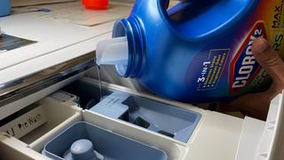 Bleach being added to a detergent drawer in a washing machine