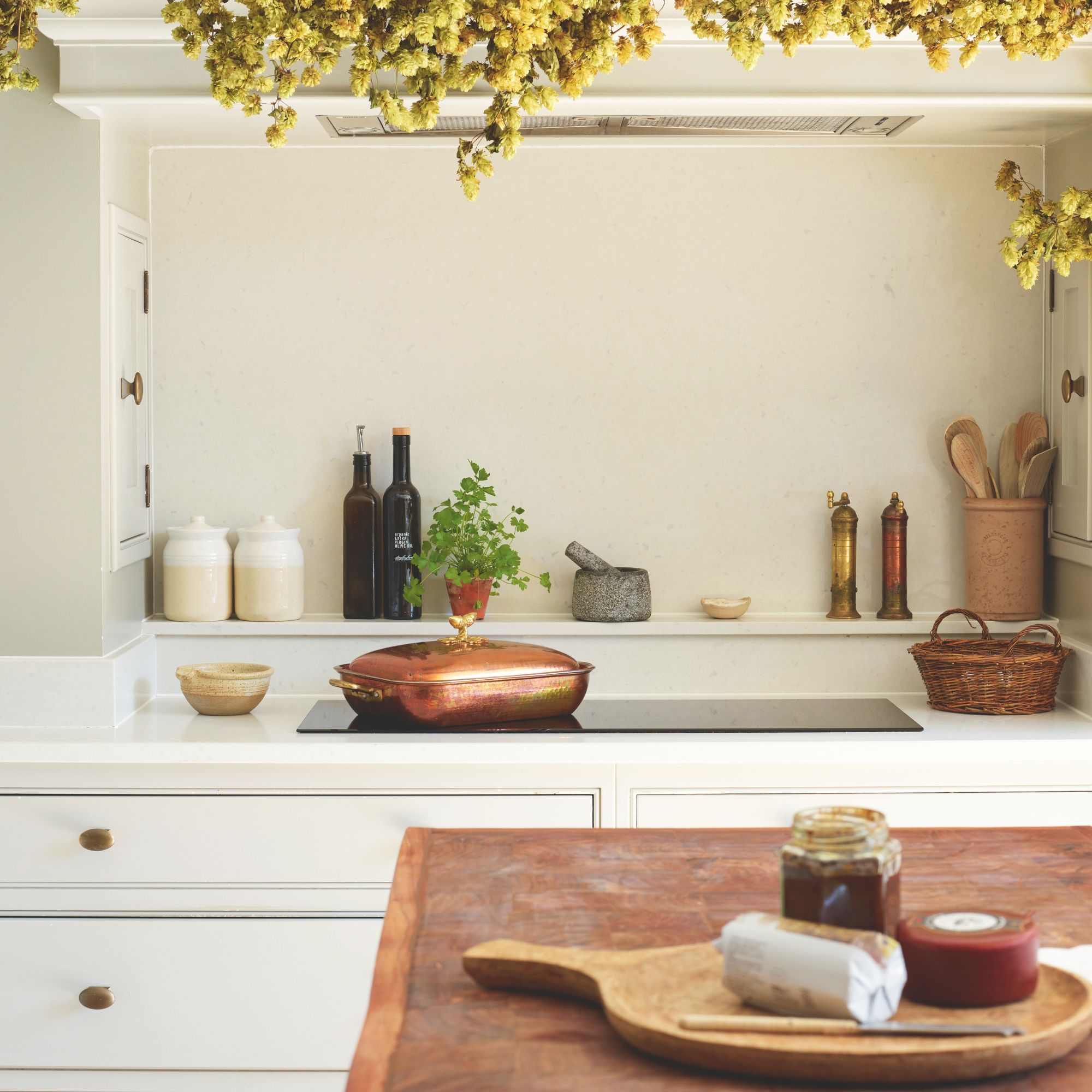 Cooking area with an induction hob, and lots of cooking utensils and jars next to and behind it