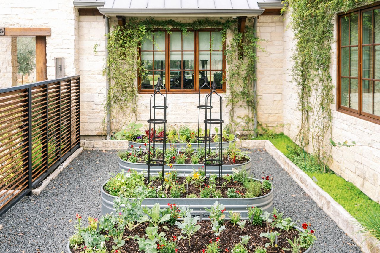 a raised container garden with vegetables planted in metal troughs