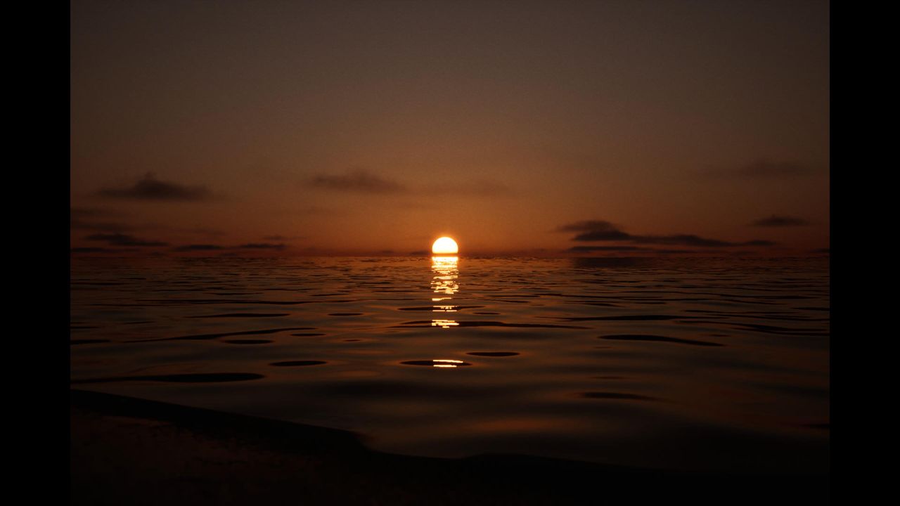 Screenshot of the photography simulator game Lushfoil Photography Sim, depicting a sunset over a body of water