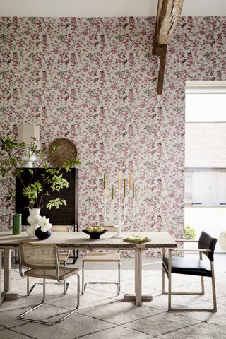 dining room with floral pink wallpaper, pale wood table, cream rug, retro chairs