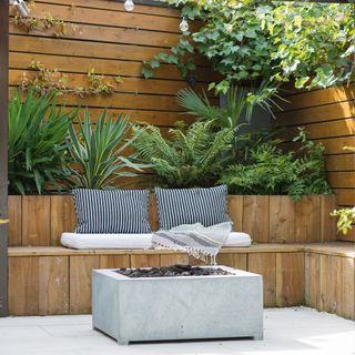 garden area with wooden bench and firepit