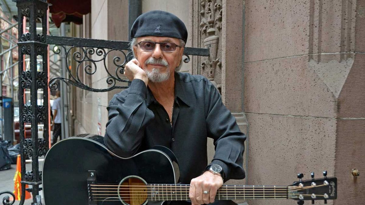 Dion holding a guitar sitting on steps