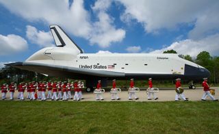 Space shuttle Enterprise is seen as the United States Marine Corp Drum and Bugle Corps and Color Guard march by at the Steven F. Udvar-Hazy Center Thursday, April 19, 2012 in Chantilly, Va