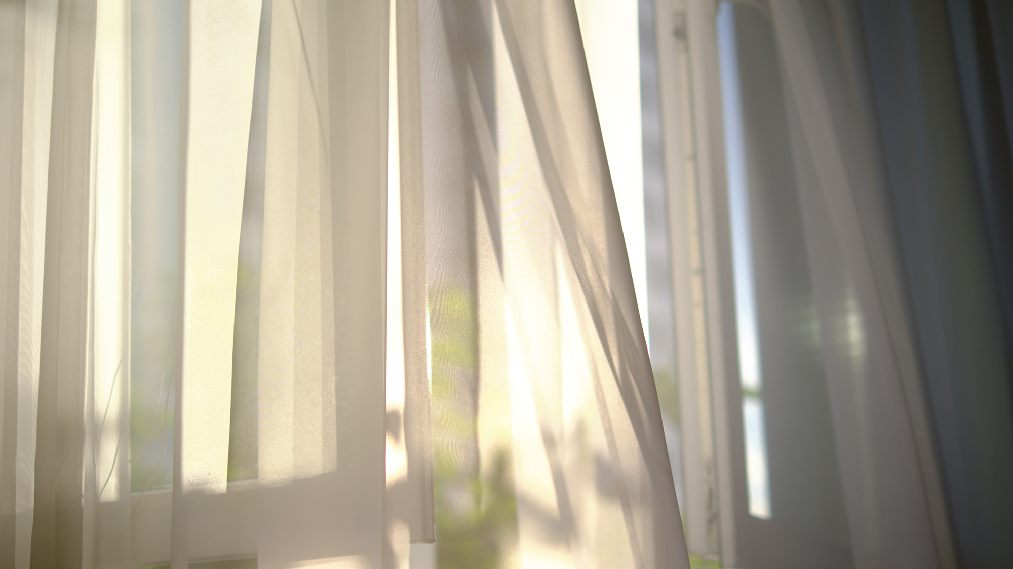 Open window with light curtains blowing in breeze